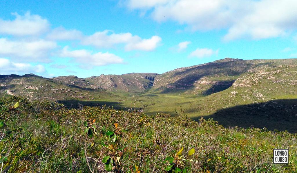Montanhas ao oeste, no vale do Mucugê. Bem ao centro é possível notar a fenda onde se encontra a nascente do Mucugê. No terreno à sua frente, o leito do rio segue serpenteando.